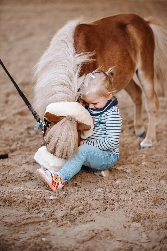Kleines Kind sitzt neben Pony