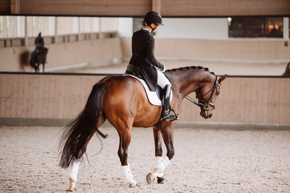 Frau reitet Pferd im Turnieroutfit