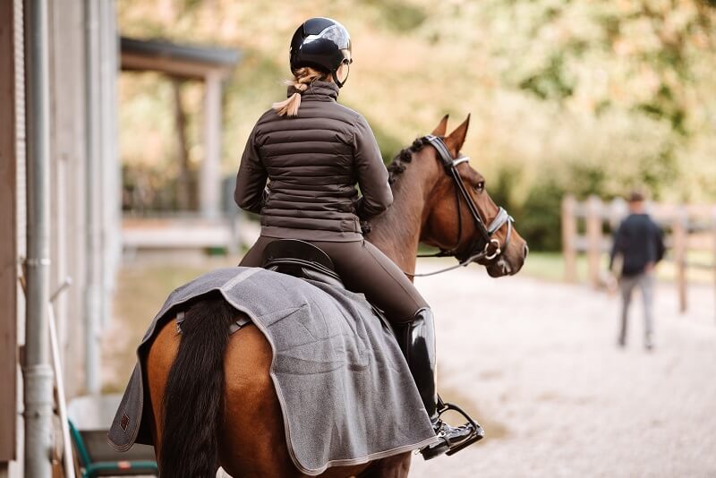 Reiterin auf Pferd mit Ausreitdecke