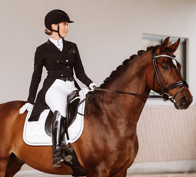 goldenes Reitabzeichen Dressurreiterin sitzt auf Pferd im Turnieroutfit