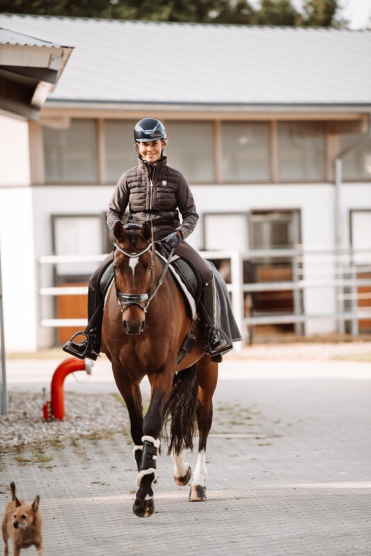 Dressur Reiten Frau reitet Pferd über Hof