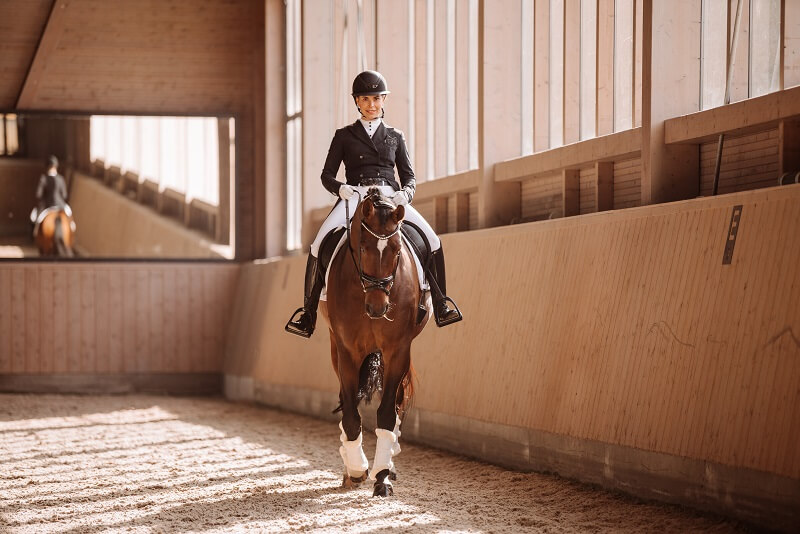 Frau reitet Pferd im Turnieroutfit