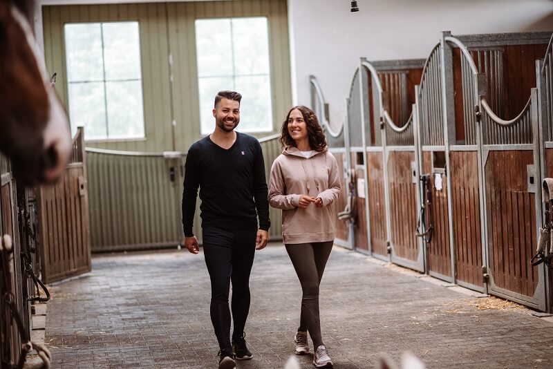 Reiten perfekter Sport Mann und Frau laufen durch den Stall