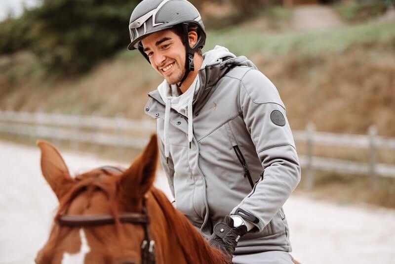 Reiter sitzt auf Pferd und lacht