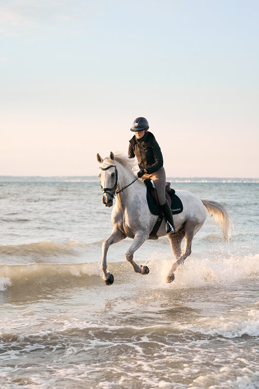 Reiterin galoppiert im Meer