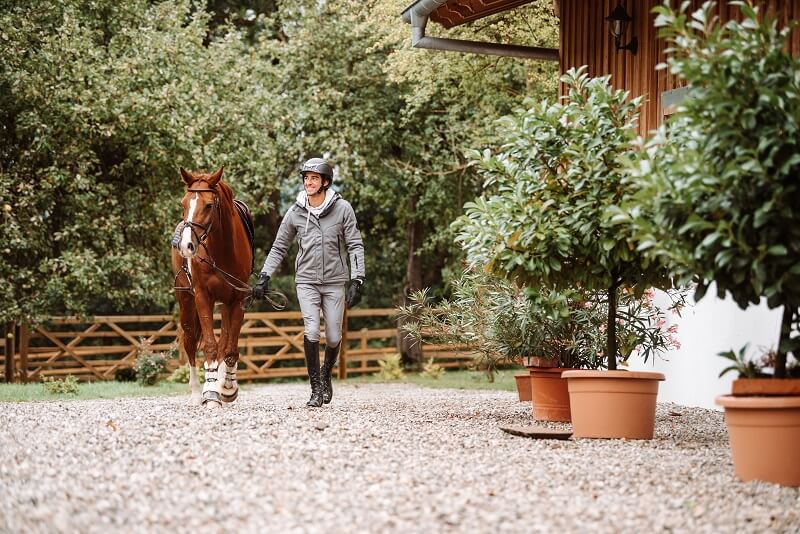 Reiter führt Pferd über Hof