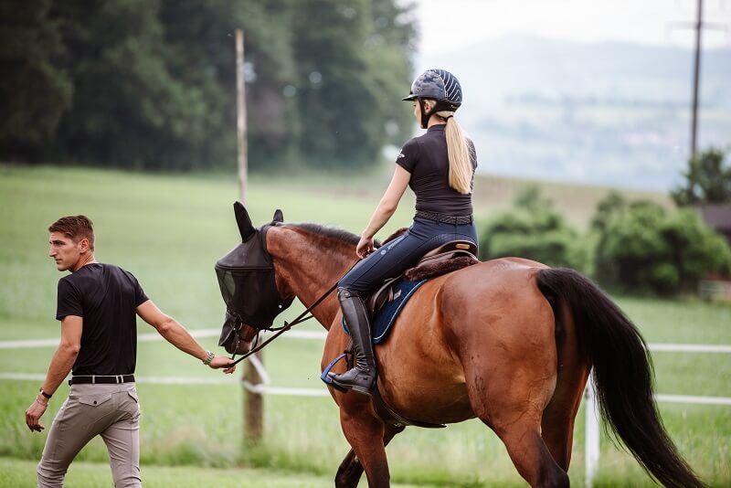 Mann führt Reiterin auf Pferd