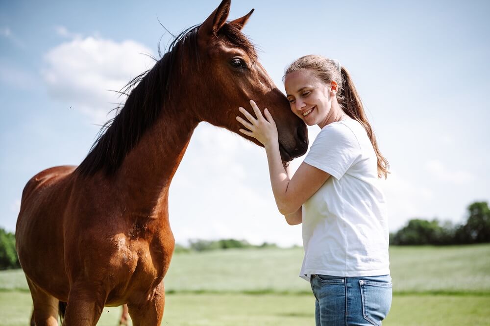 Frau mit Pferd auf Koppel