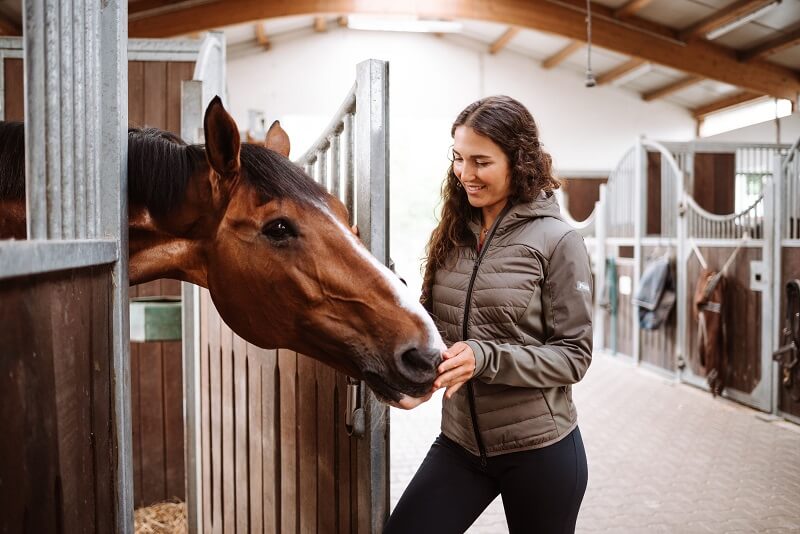 Kenzie Dysli Frau streichelt Pferd in der Box