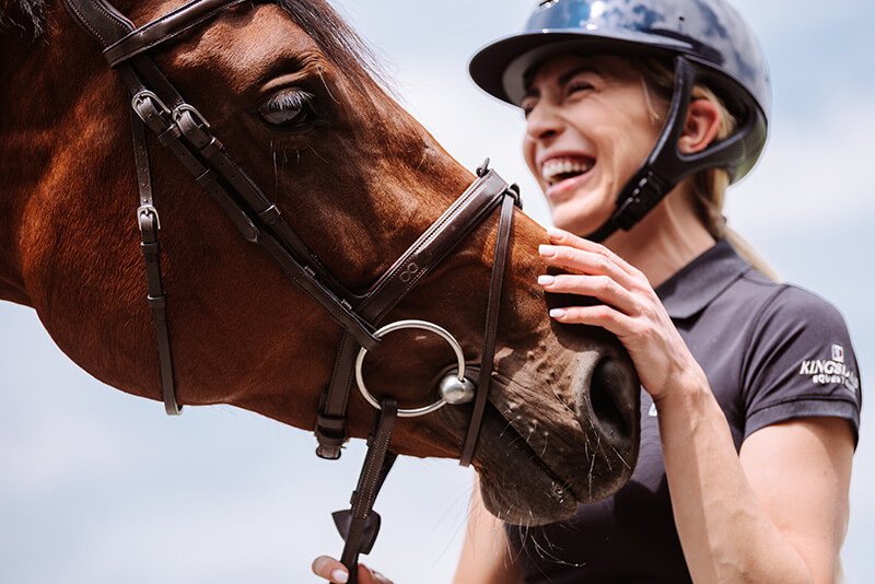 Frau hält Pferd und lacht